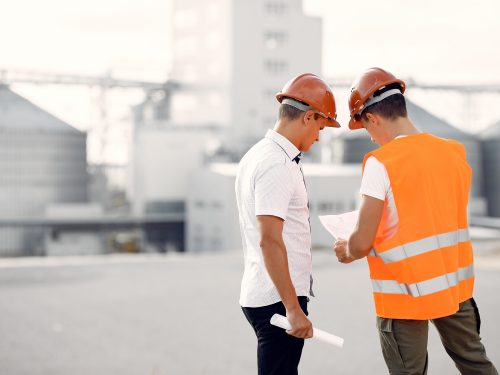 Engineers near the factory. Mtn in a helmet. Inspector looks at the building.